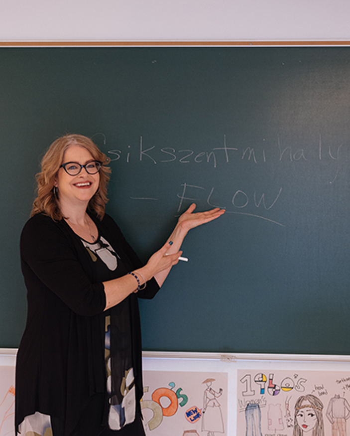 Amy Lemmon smiling and writing words on chalkboard
