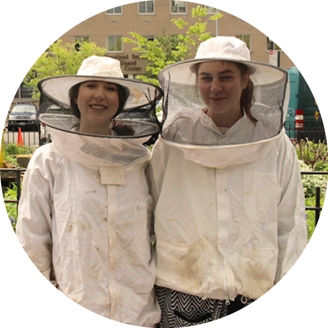 two students wearing bee keeper suits