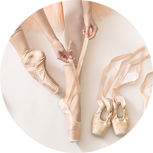 ballet dancer's legs with several pairs of pointe shoes on display
