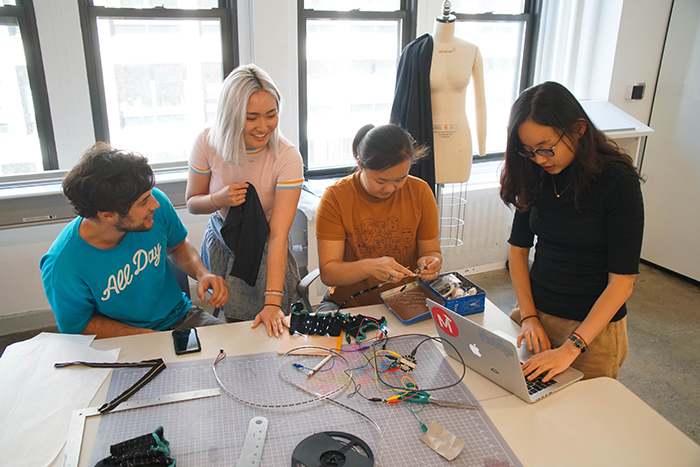 FIT and visiting students from MIT test products with computer at the Advanced Fibers and Fabrics workshop at the Brooklyn Navy Yards